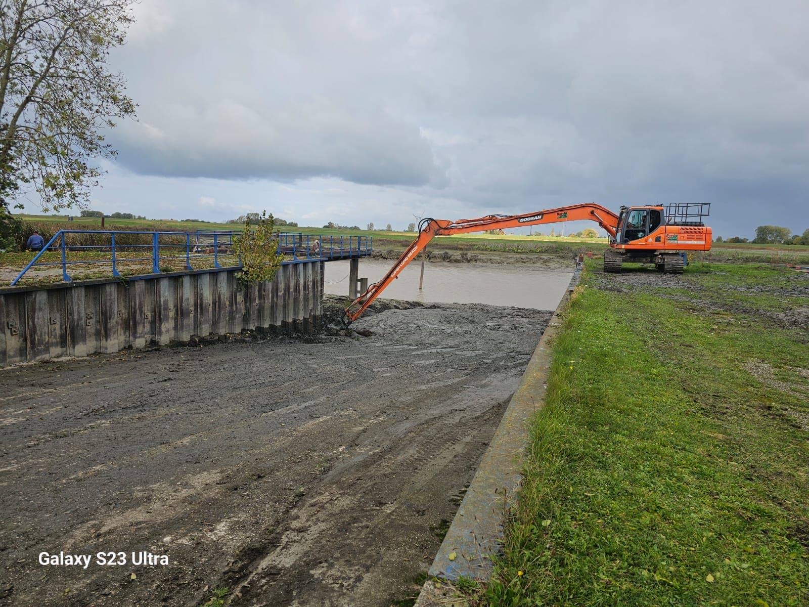 Bagger reinigt einen Graben an einer Brücke im Rheiderland.