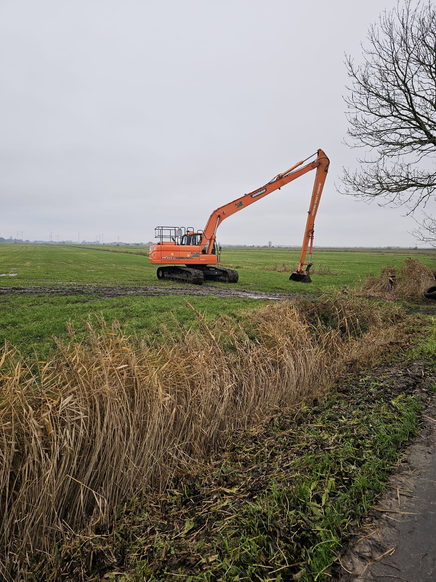 Langarmbagger von Landschaftpflege Borde bei der Grabenreinigung in offener Feldlandschaft.