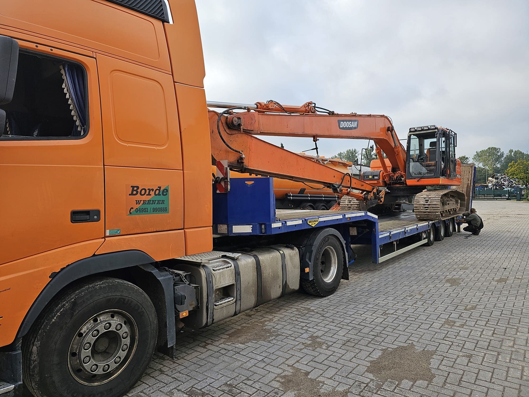 Volvo-Sattelzug von Landschaftpflege Borde transportiert einen Doosan-Bagger auf einem Tieflader.